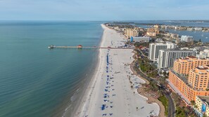A coastal cityscape with a beach, high-rise buildings, and a pier extending into the sea. - Spacious 3-bedroom family-friendly condo in Clearwater Beach (Clearwater)