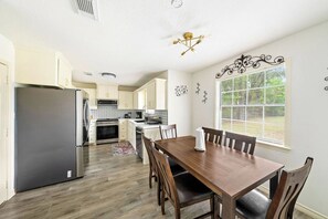 A kitchen with a refrigerator, stove, and dining table with chairs. - Serene 4-bedroom house with AC in charming Spring TX 77386 (Spring)