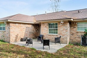 A brick house with a covered patio area and outdoor furniture. - Serene 4-bedroom house with AC in charming Spring TX 77386 (Spring)