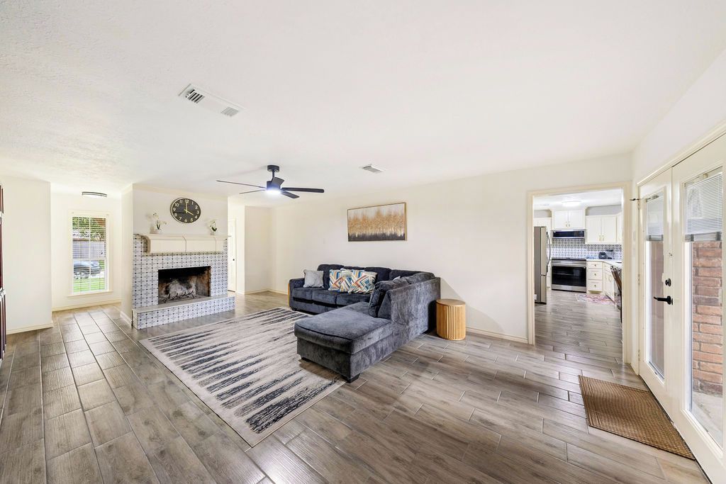 A living room with a fireplace, a sofa, and a ceiling fan.