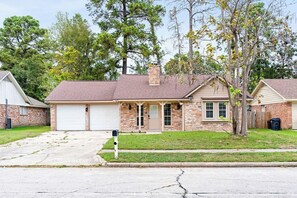 A residential house with a garage, a front porch, and a brick exterior. - Serene 4-bedroom house with AC in charming Spring TX 77386 (Spring)