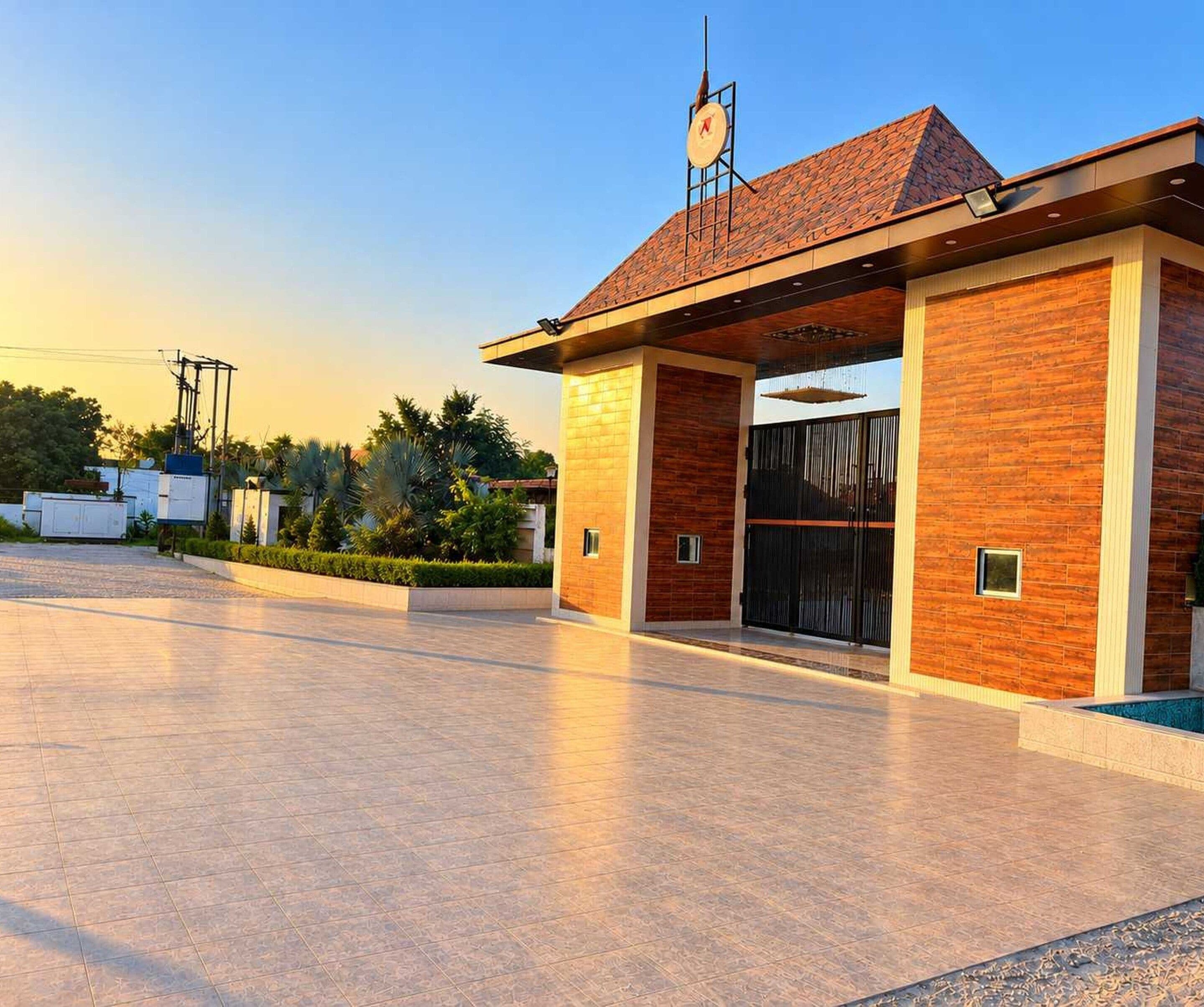 A modern building with a brick facade, a large entrance gate, and a clock on the roof.