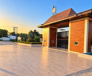 A modern building with a brick facade, a large entrance gate, and a clock on the roof. - Deluxe Red Chilly 3.O (Gorakhpur)