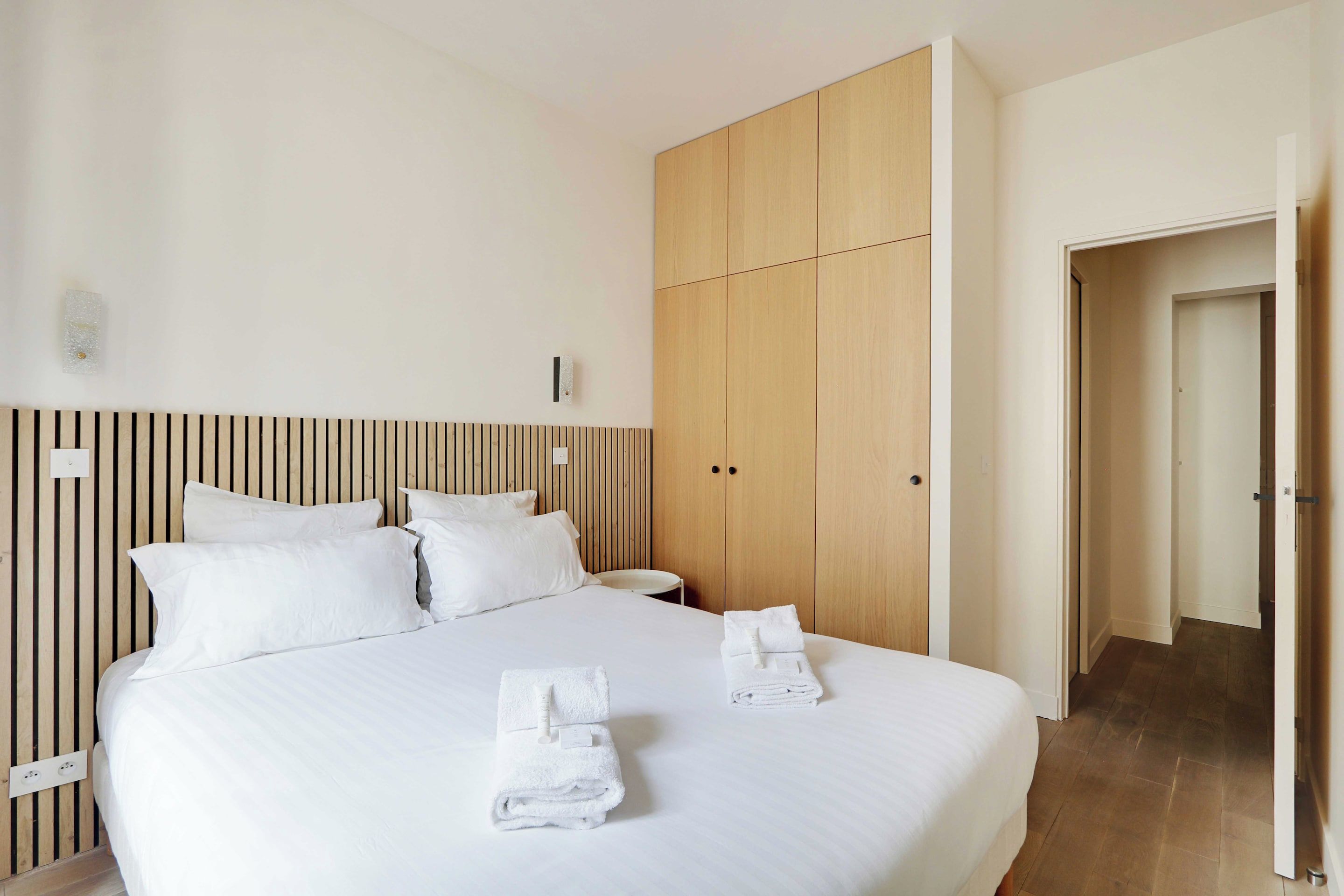 Une chambre d’hôtel avec un lit, une armoire en bois et une porte de salle de bain.