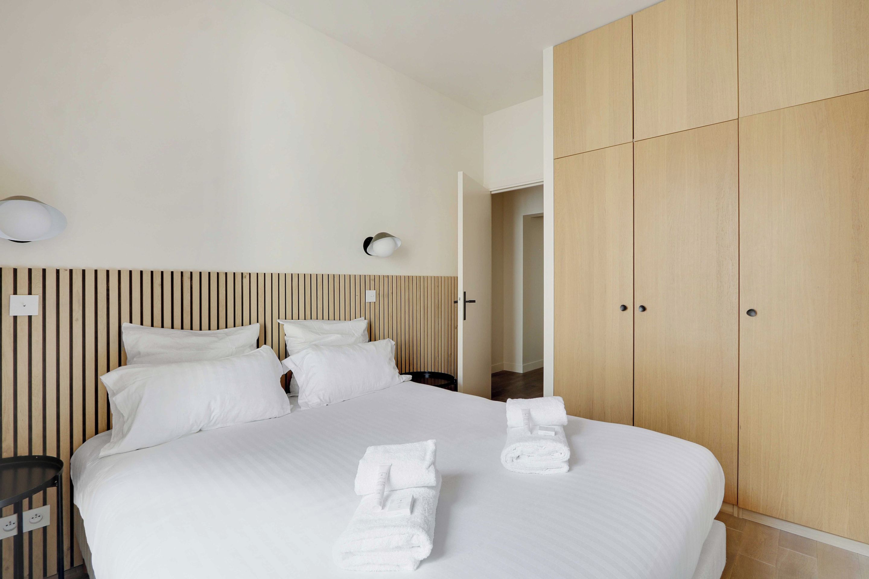 A hotel room with a large bed, wooden headboard, and a wardrobe.