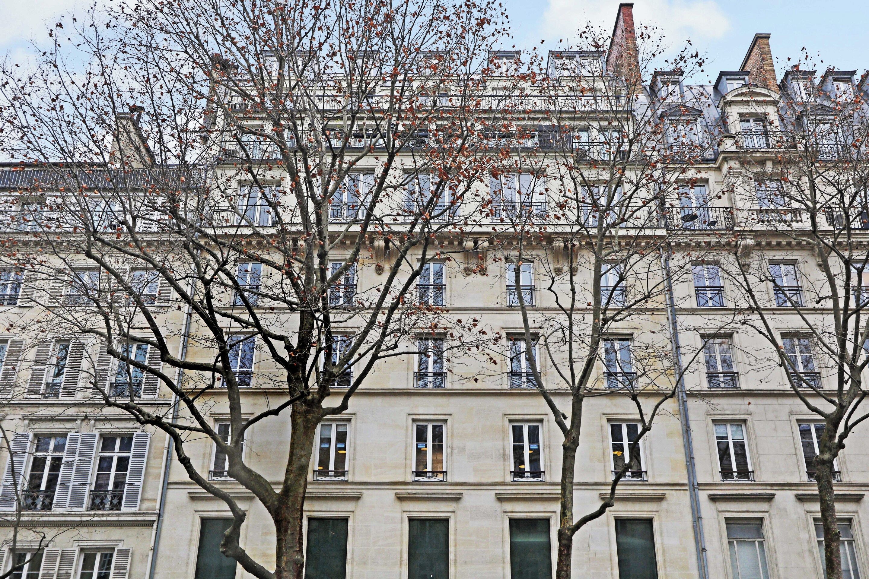 Un immeuble à plusieurs étages de style architectural classique, caractérisé par des fenêtres disposées de manière symétrique et une entrée centrale.