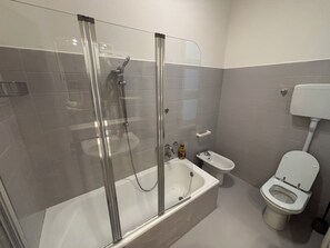 Une salle de bain avec une douche à parois de verre, une baignoire, des toilettes et un petit lavabo.