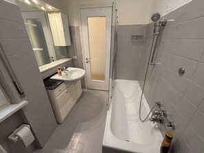 A bathroom with a bathtub, a sink, a mirror, and a shower. - New Listing (Verona)