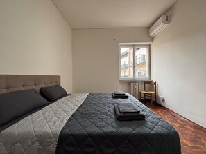 Une chambre à coucher avec un lit, une fenêtre, un radiateur et une chaise.