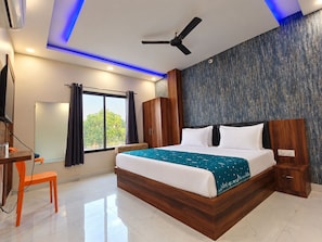 Una habitación de hotel moderna con una cama grande, un escritorio y un ventilador de techo.