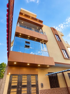 A multi-story building with a modern architectural design, featuring balconies, large windows, and a combination of glass and solid materials.