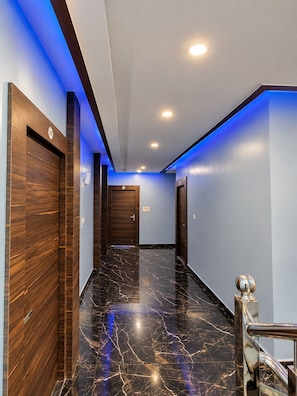 A modern hallway with marble flooring, wooden paneling, and blue LED lighting. - Arivoo. Hotel Green Leaf (Datia)
