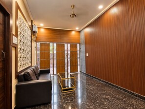 A modern lobby with a black marble floor, a leather sofa, and a decorative wall panel.