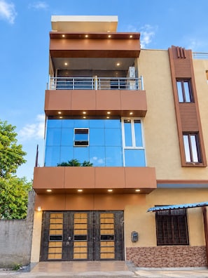 A multi-story building with a flat roof, a balcony on the upper floor, and a gated entrance. - Arivoo. Hotel Green Leaf (Datia)