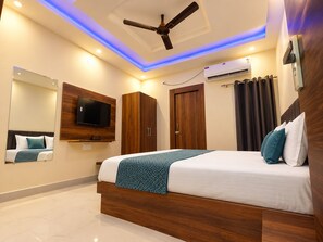 Un dormitorio moderno con cama, ventilador de techo, televisor montado y aire acondicionado.