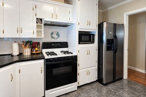 A kitchen with white cabinets, a stove, a microwave, and a refrigerator. - Home on the Bayou Cozy 3BR + 2BA Stay in a Quiet Houma Neighborhood (Houma)