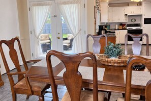 A dining area with a wooden table and chairs, a wicker basket, and a potted plant. - Home on the Bayou Cozy 3BR + 2BA Stay in a Quiet Houma Neighborhood (Houma)