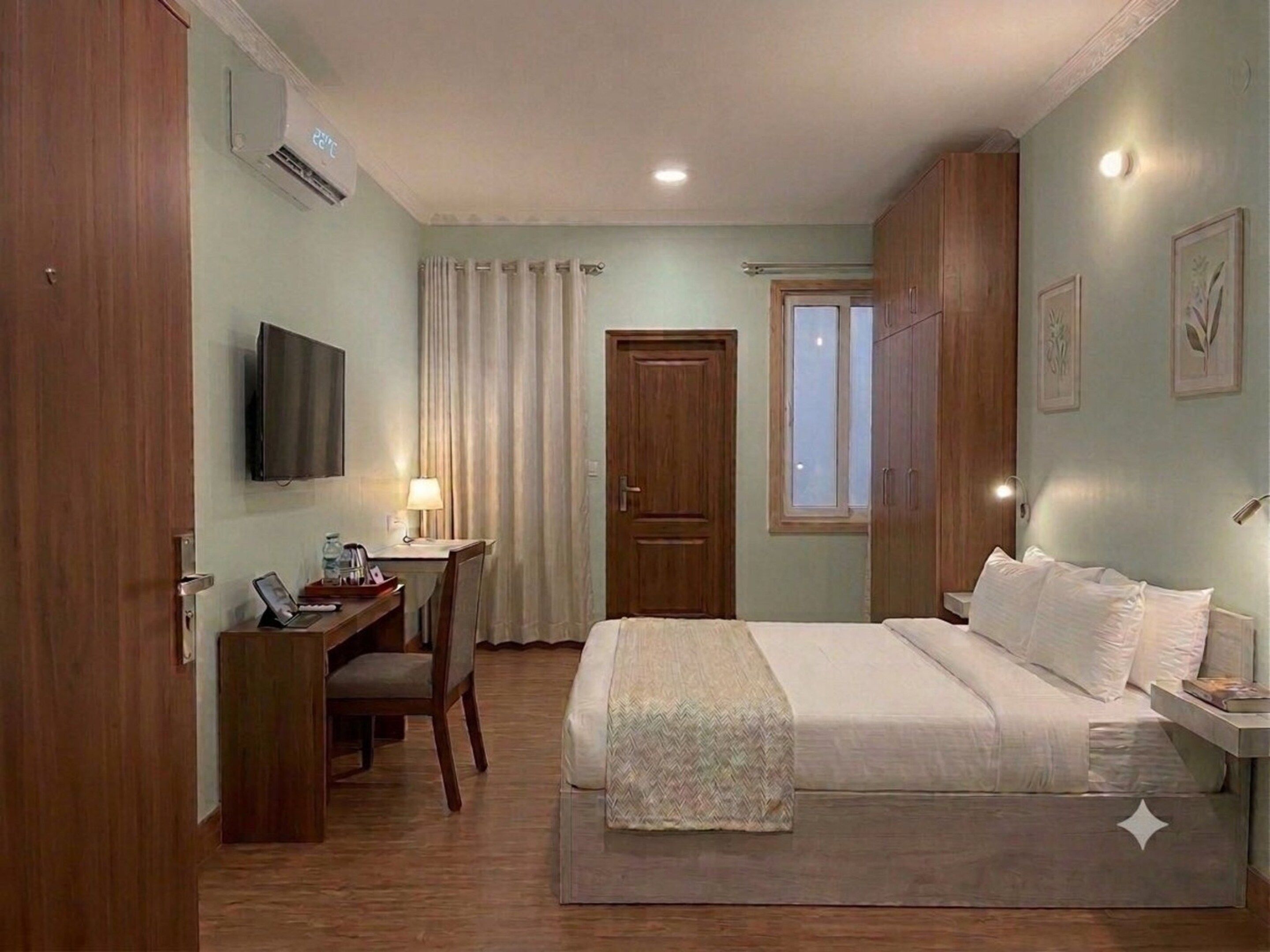 Habitación de hotel con cama, escritorio, silla, televisión y armario.