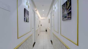 A hallway with white walls, gold trim, and artwork.