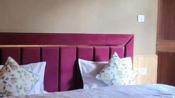 Una cama con cabecera, almohadas y colcha.