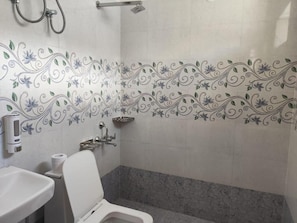 A bathroom with a toilet, sink, and shower area.