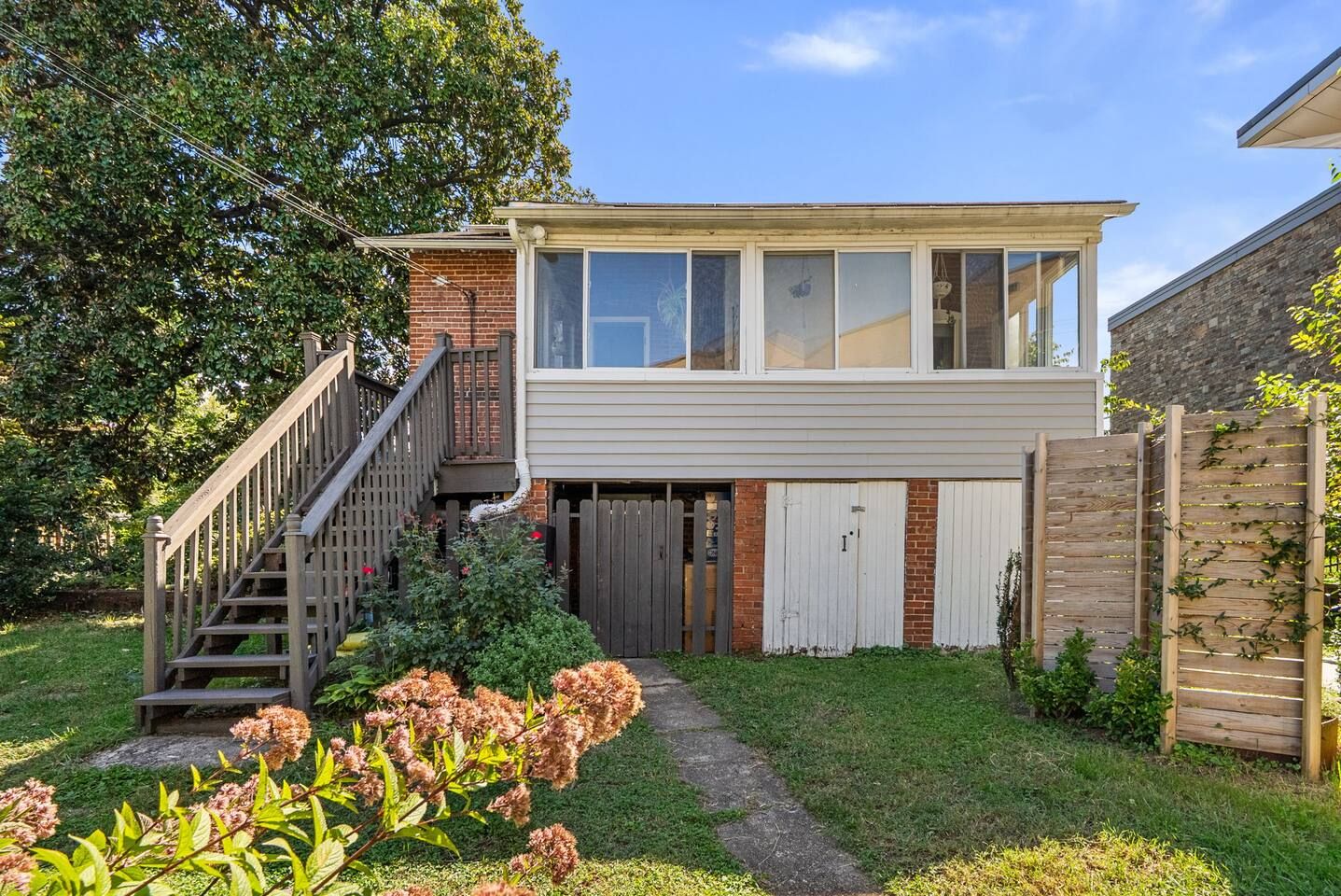 Ein zweigeschossiges Haus mit sichtbarer Treppe, einer Garage und einem umzäunten Garten.
