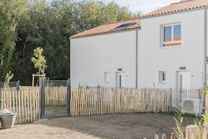 A two-story building with a white exterior, a tiled roof, and a fenced backyard. - Quartz - Jardin - Proche plage (Saint-Hilaire-de-Riez)