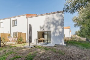Una casa moderna con patio, una porta scorrevole in vetro e un piccolo giardino.