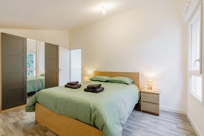 A bedroom with a bed, bedside tables, a lamp, and a wardrobe. - Quartz - Jardin - Proche plage (Saint-Hilaire-de-Riez)