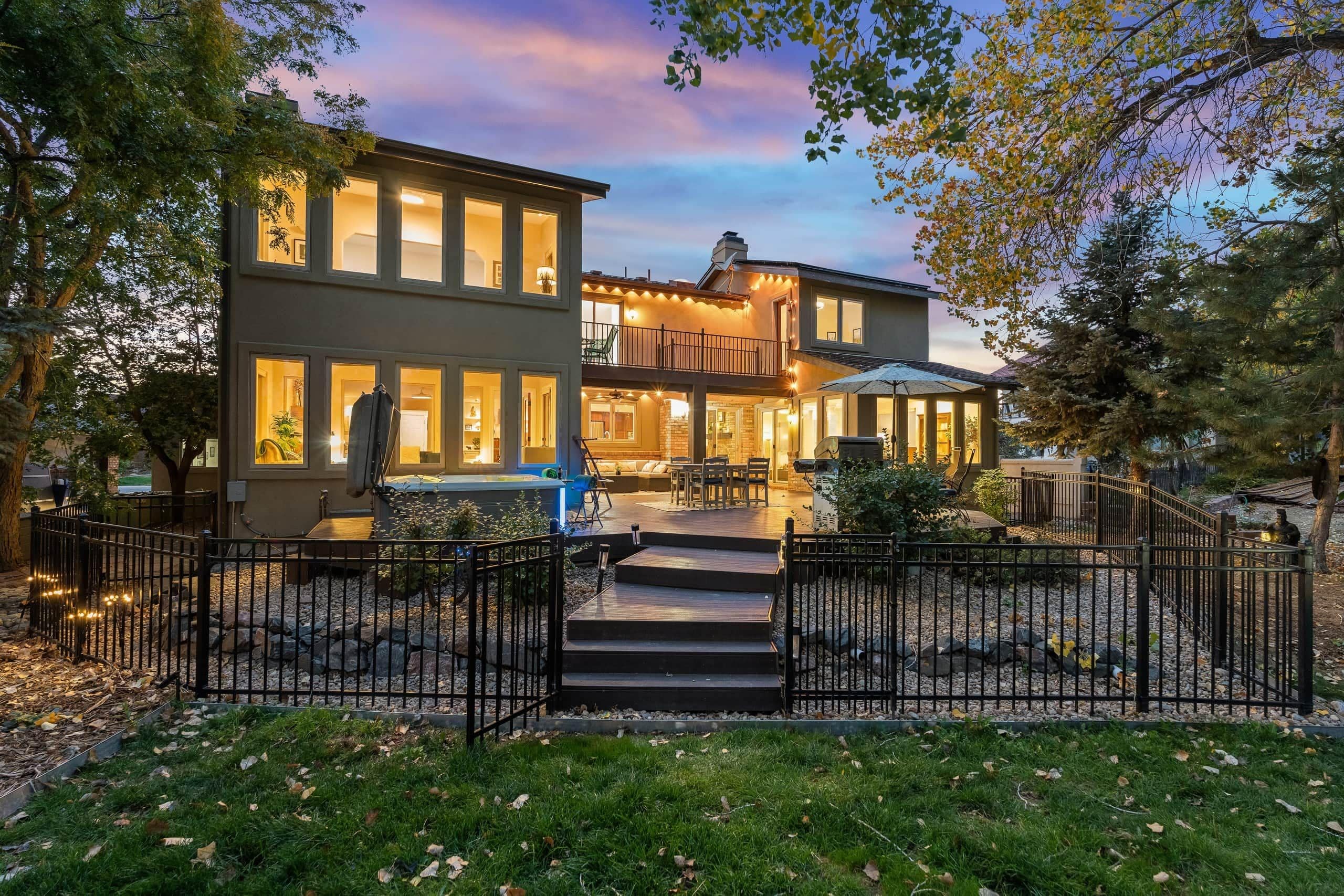 A two-story house with a balcony, a patio, and a stone pathway leading to the entrance.