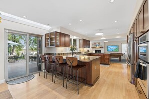 A modern kitchen with a central island, bar stools, and built-in appliances. - Heron Pond: Lakeside 5BR, Hot Tub+Billiards (Broomfield)
