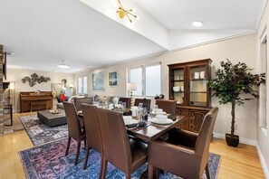 A dining area with a wooden table set for six, surrounded by brown leather chairs. - Heron Pond: Lakeside 5BR, Hot Tub+Billiards (Broomfield)