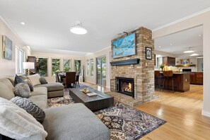 A spacious living room with a fireplace, a dining area, and a kitchen. - Heron Pond: Lakeside 5BR, Hot Tub+Billiards (Broomfield)