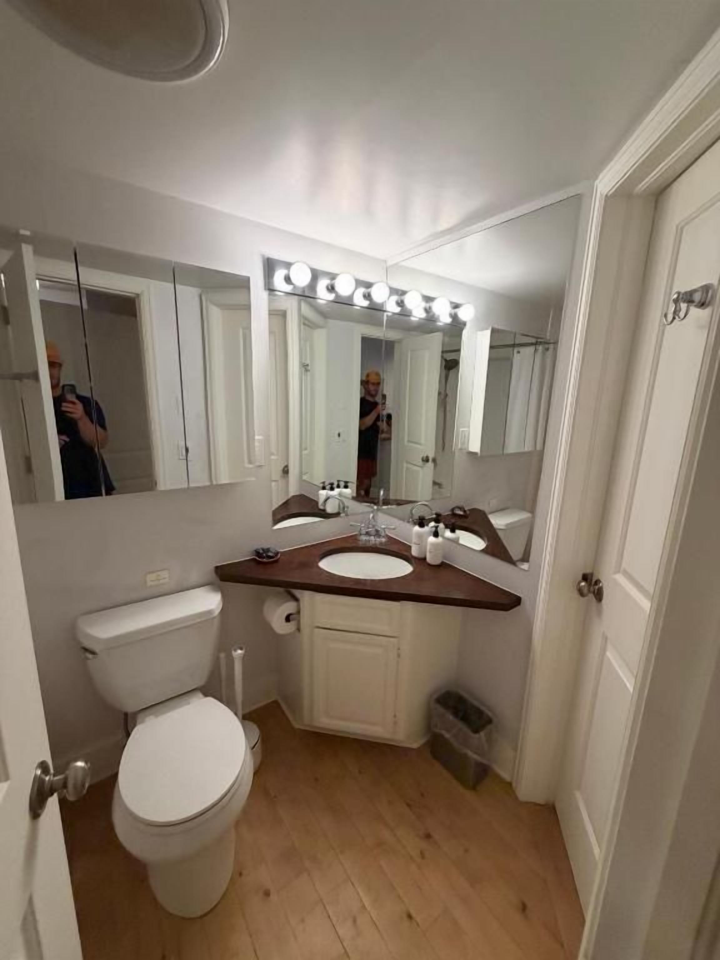 A bathroom with a toilet, sink, mirror, and vanity.