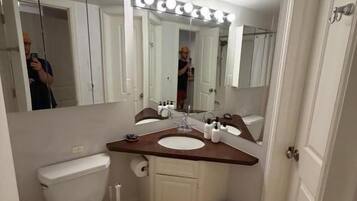 A bathroom with a toilet, sink, mirror, and vanity.