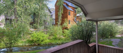 A view from a covered area overlooking a river with a building in the background.