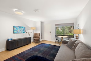 A modern living room with a sofa, a coffee table, a dining table with chairs, a lamp, and a painting on the wall. - Two Sisters Telluride (Telluride)