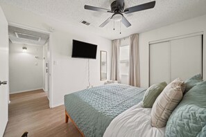A bedroom with a bed, a ceiling fan, a TV, and a door leading to another room. - Your Home Away From Home - Cozy Retreat (Bakersfield)