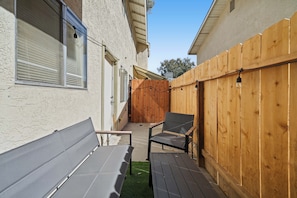 A patio area with a wooden fence, a bench, and a table. - Your Home Away From Home - Cozy Retreat (Bakersfield)