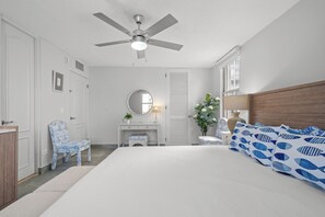 A bedroom with a bed, a desk, a chair, a ceiling fan, and a window. - Castillo Caribe by Otium (San Juan)