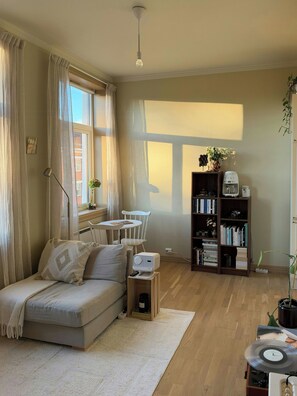 Ein gemütliches Wohnzimmer mit einer Couch, einem Couchtisch, einem Bücherregal und einem Plattenspieler.