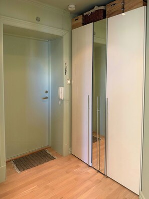 Ein Zimmer mit Holzboden, einer weißen Tür, einem weißen Kleiderschrank und einem kleinen Teppich.