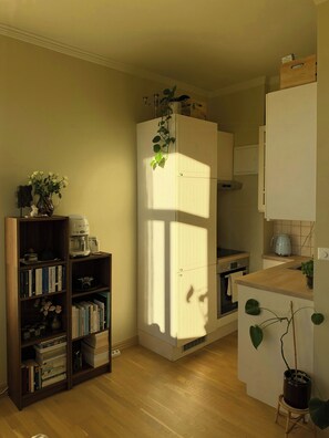 Eine kleine Küche mit einem eingebauten Kühlschrank, einem Holzregal und einem Blumentopf.