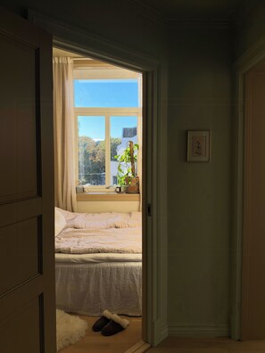 A bedroom with a bed, a window, and a potted plant. - A travel-curated flat in the heart of Grünerløkka (Oslo)