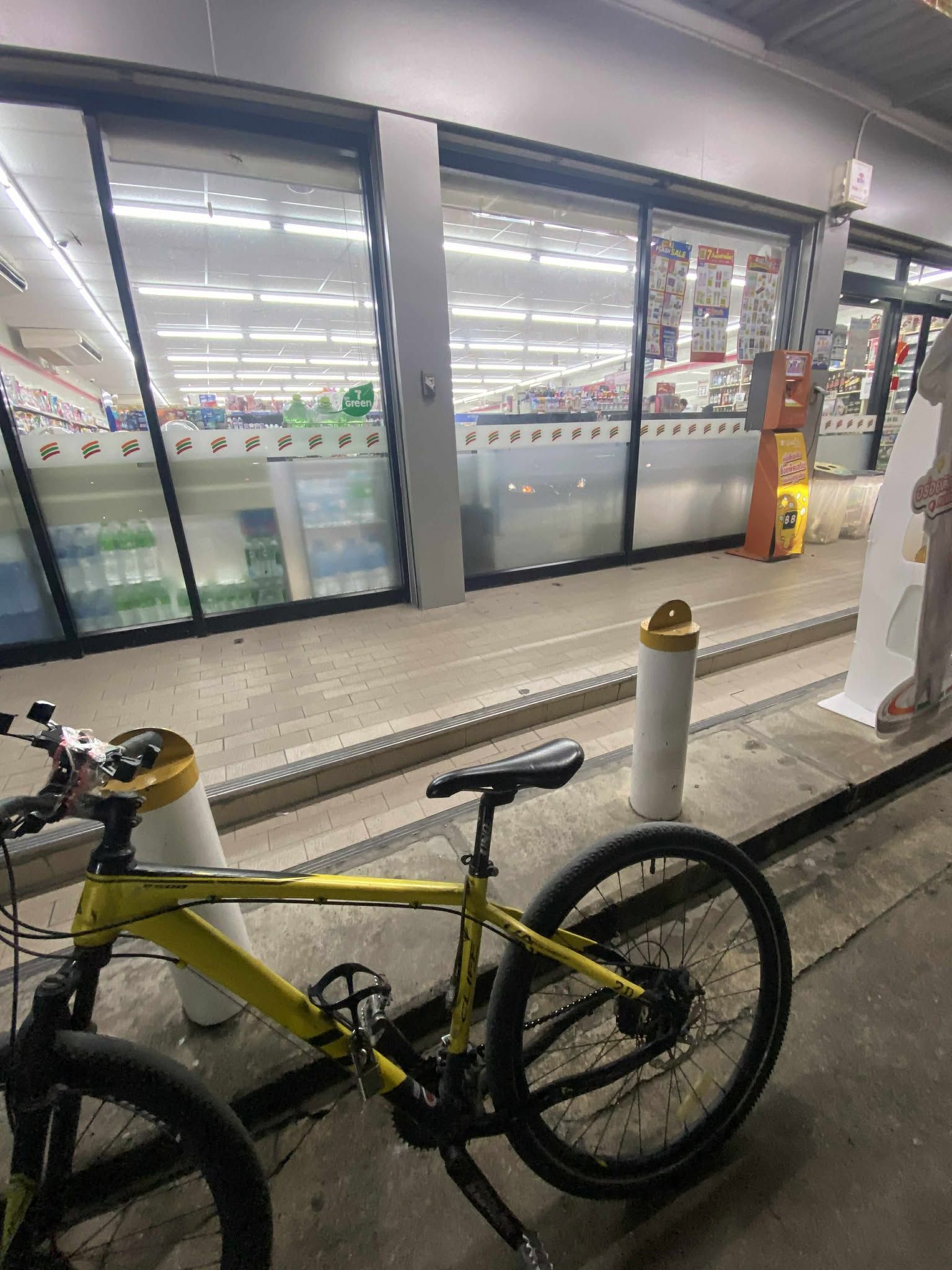 A bicycle parked near a store entrance with a tiled floor and glass doors.