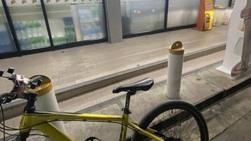 A bicycle parked near a store entrance with a tiled floor and glass doors.