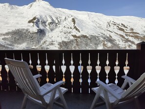 A balcony with two white chairs facing a snow-covered mountain. - Comfortable apartment - 4 guests (Les Menuires)