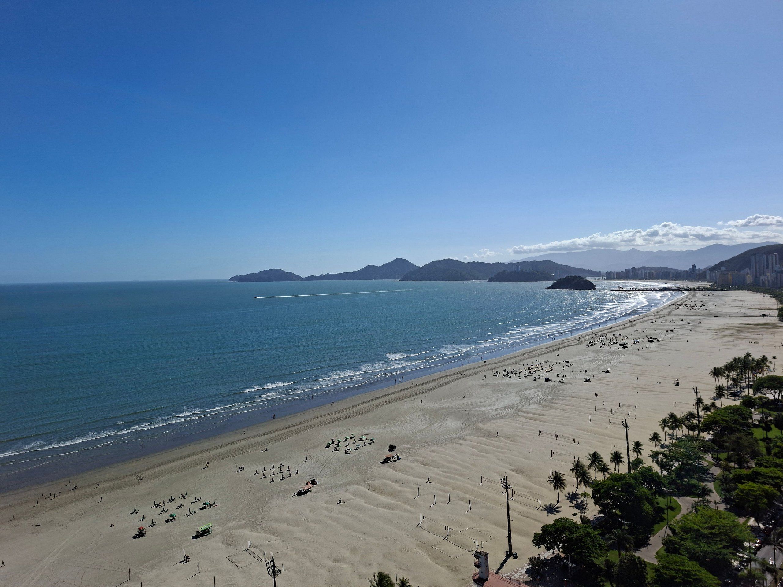 A wide beach with a clear view of the ocean and distant mountains.