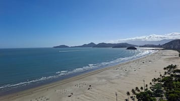 A wide beach with a clear view of the ocean and distant mountains.