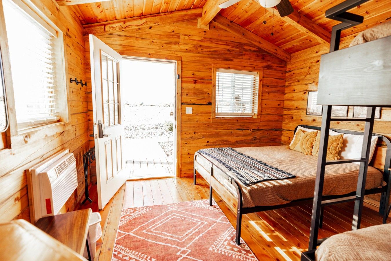 A cozy cabin room with a bed, a table, and a window.